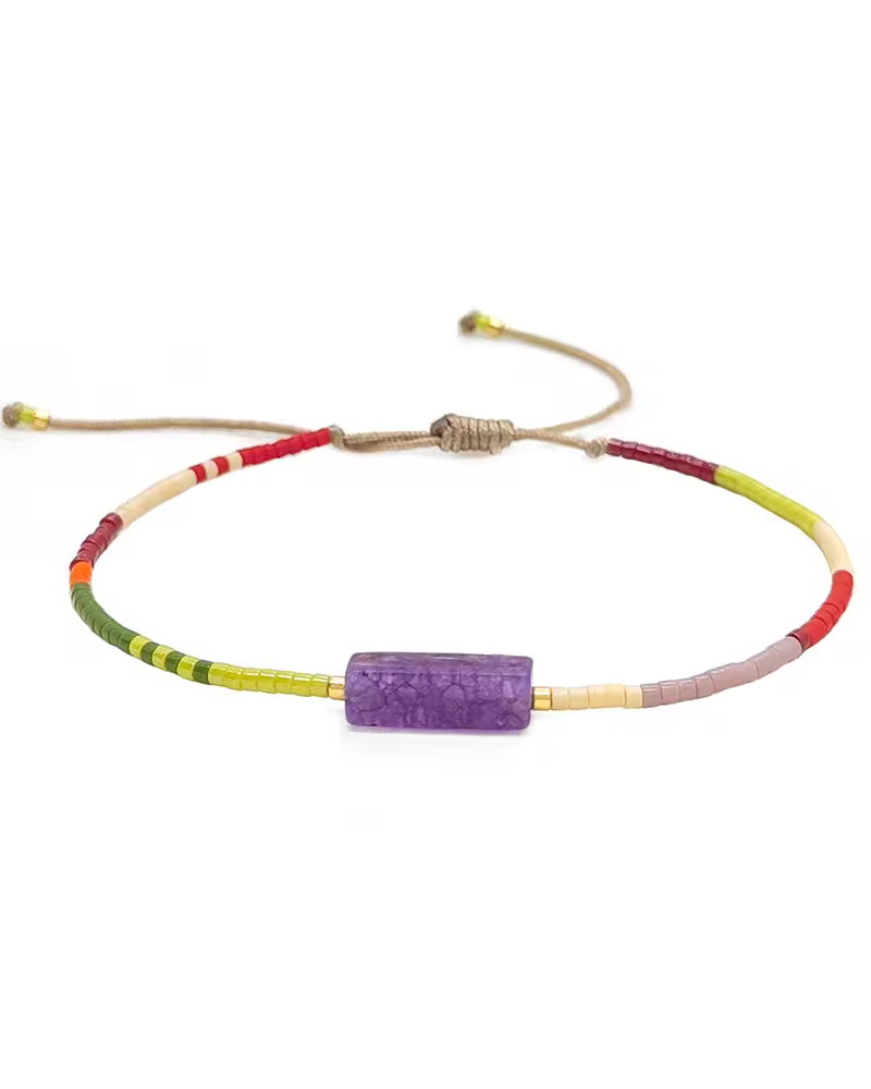 Multicolored bracelet with a purple bead on a white background