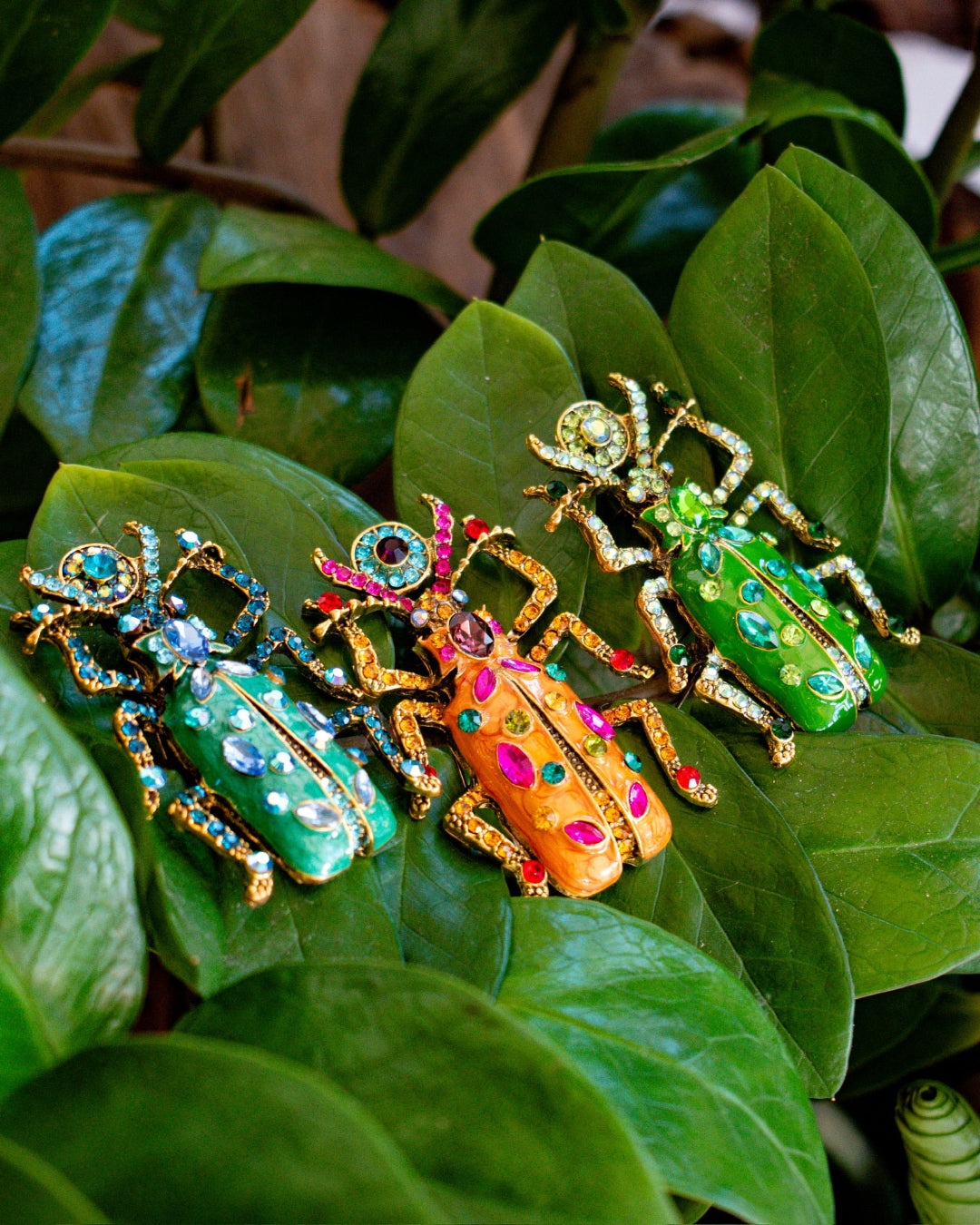 Colorful beetle-shaped jewelry pieces on green leaves