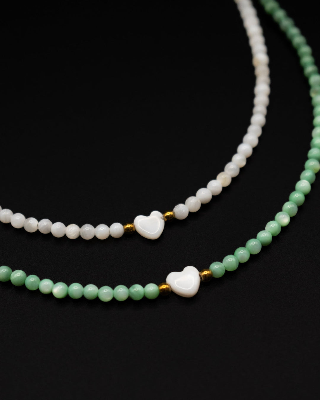 Two beaded necklaces with heart-shaped beads on a black background