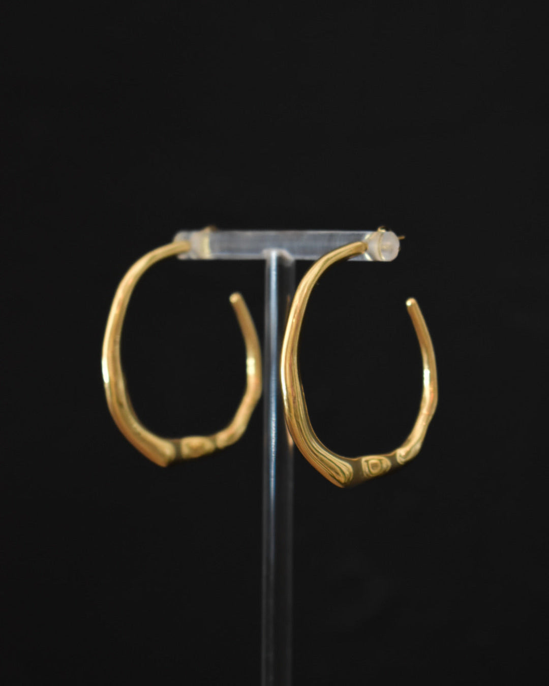 Pair of gold hoop earrings on a black background