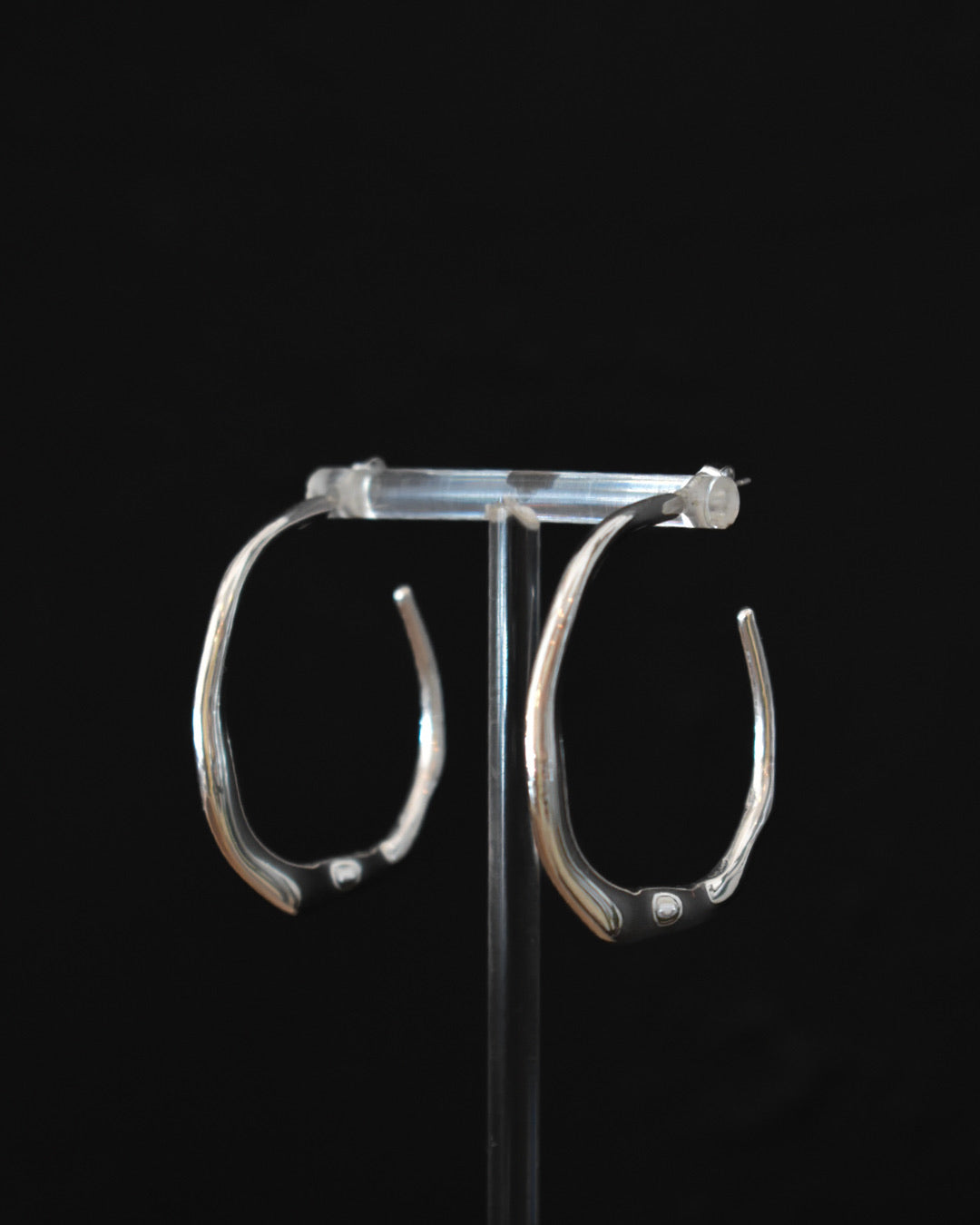 Silver hoop earrings on a black background