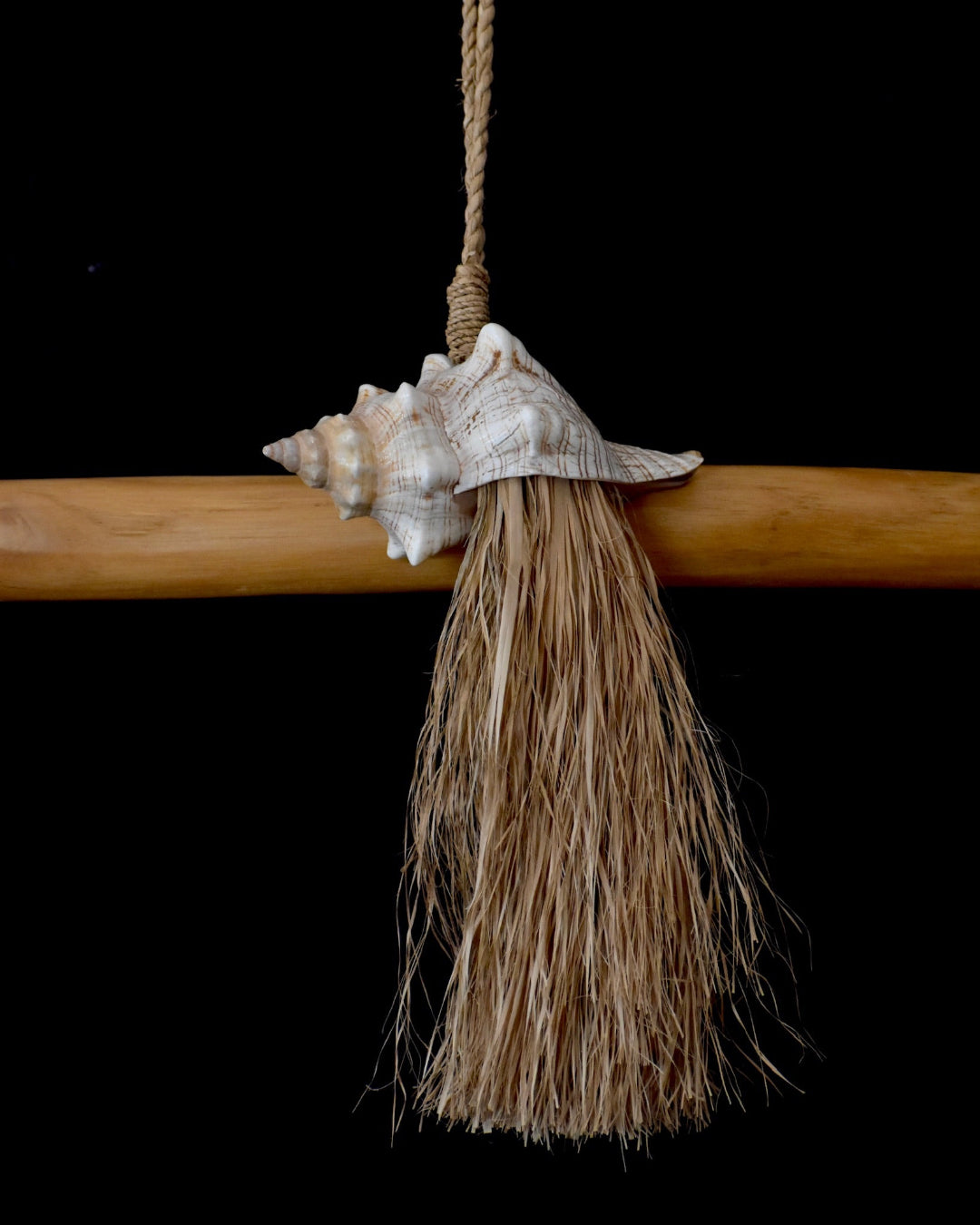 Decorative broom with a shell and tassel on a black background