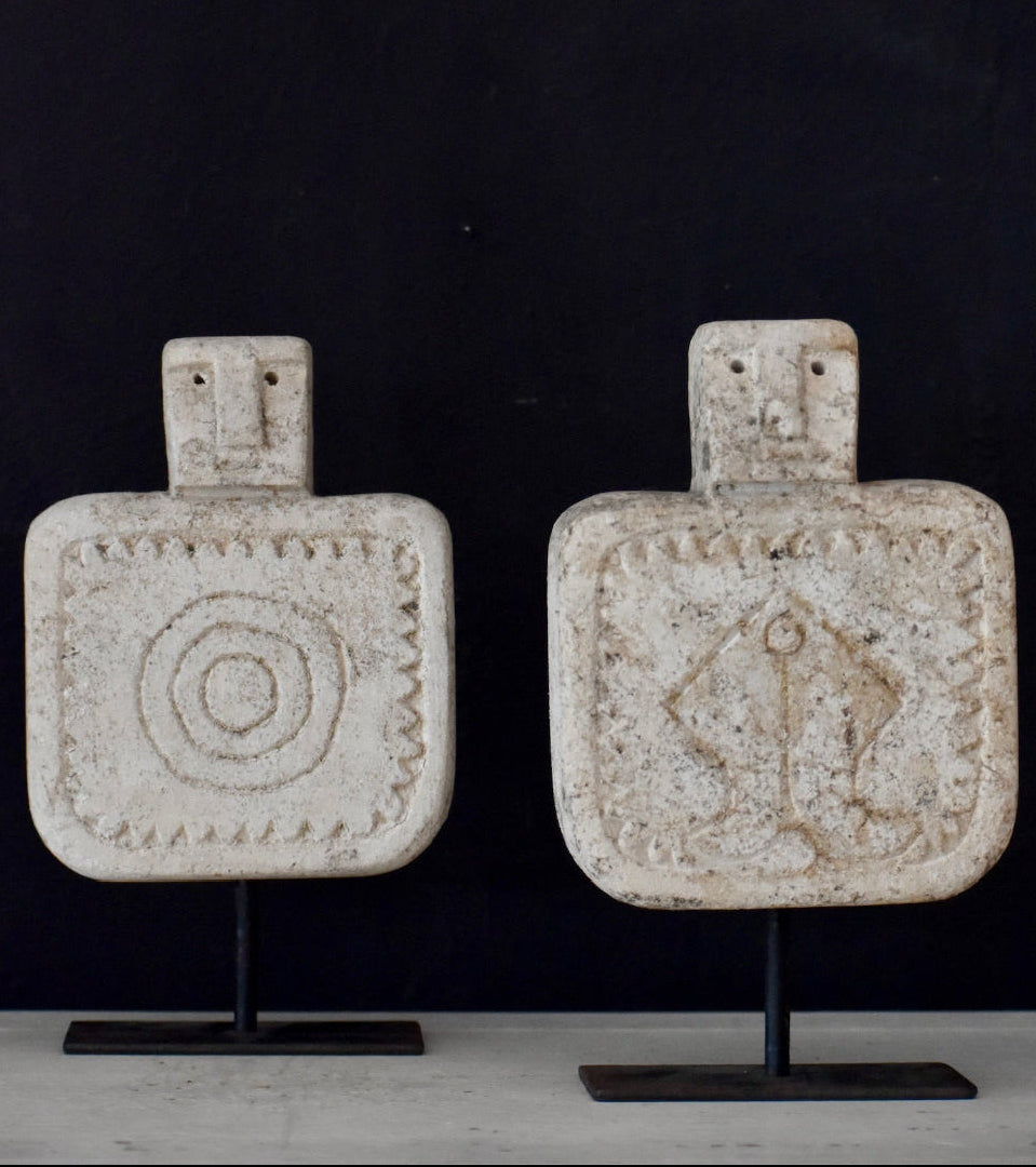 Two decorative bottles with unique designs on stands against a dark background