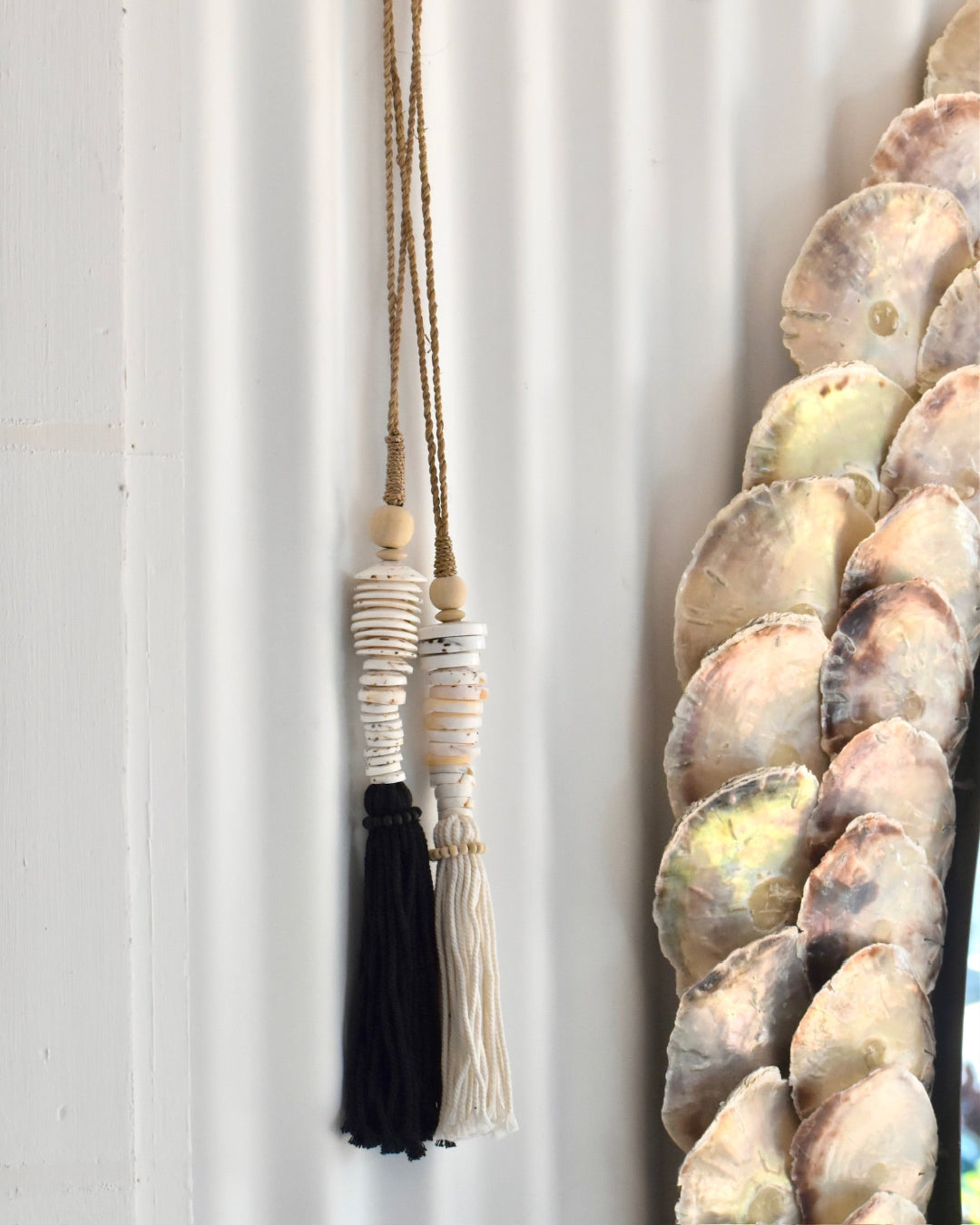 Decorative wall piece with shell and bead design against a white background