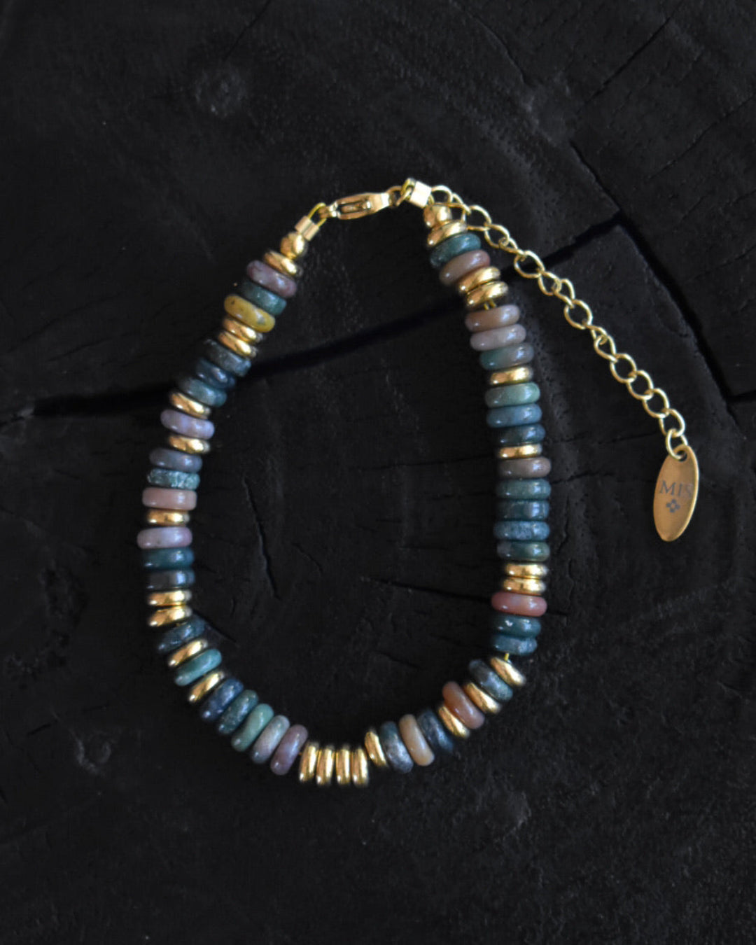 Beaded bracelet with gold accents on a dark surface