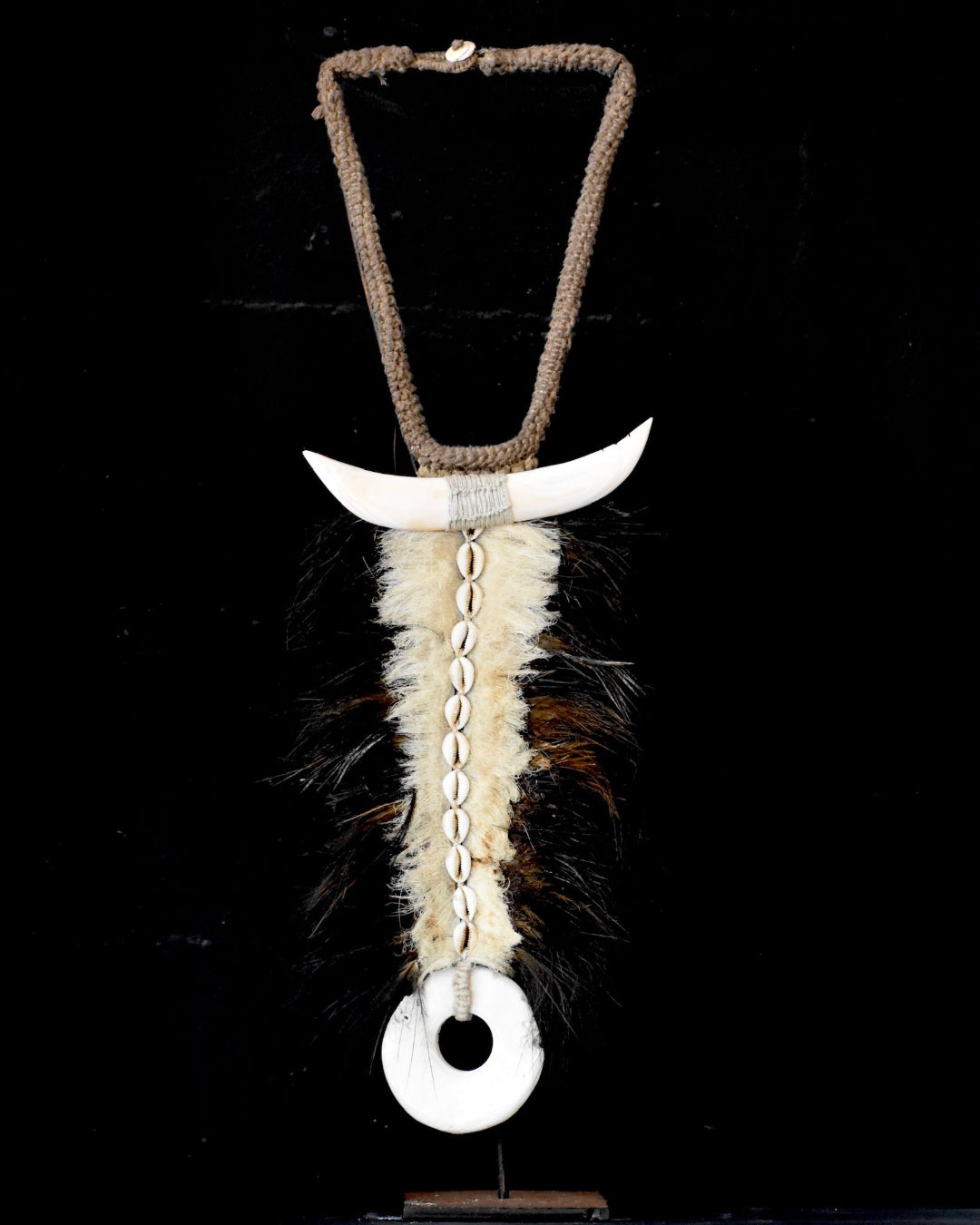 Decorative item with a horn, feathers, and beads on a black background