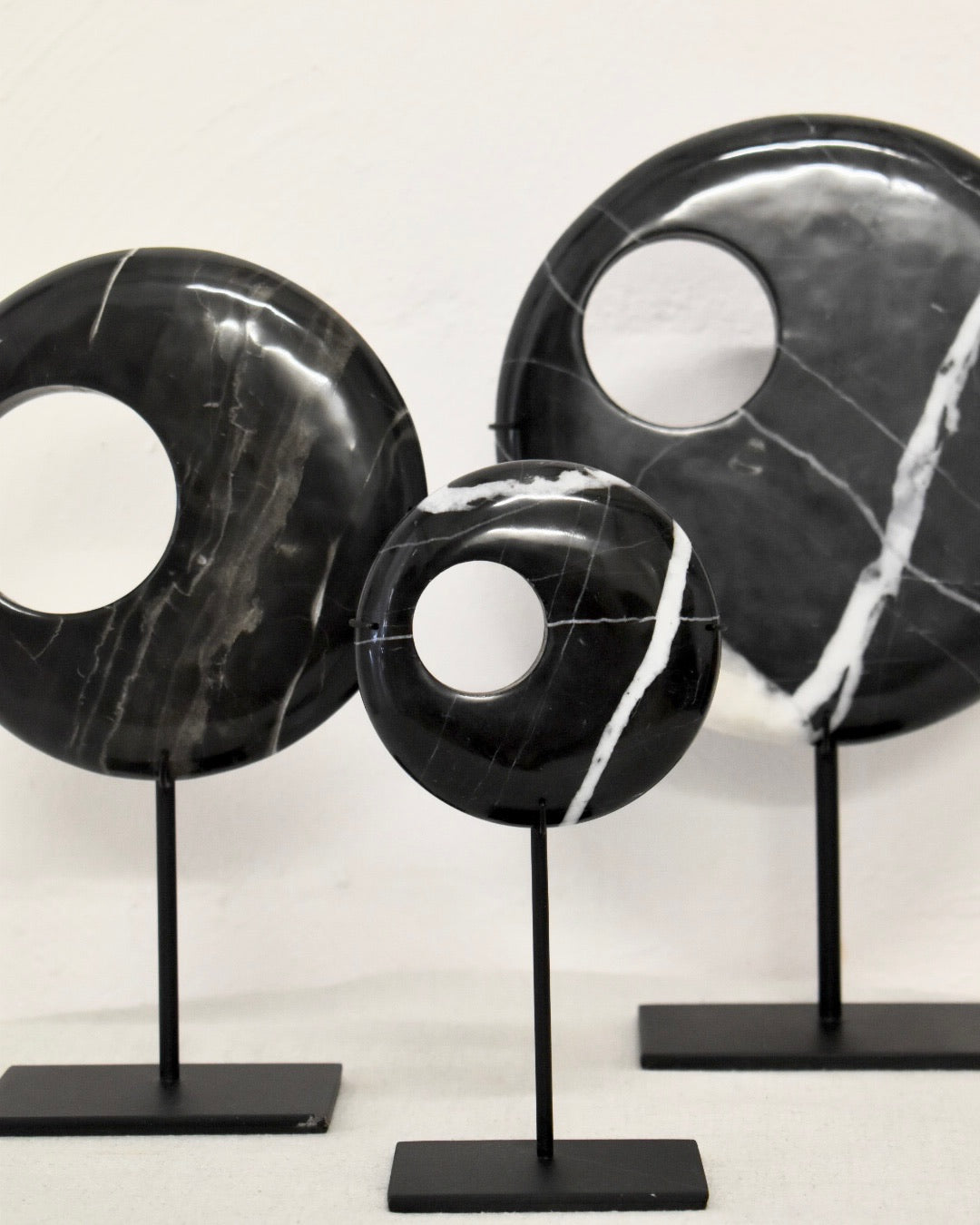 Black marble decorative items on stands against a white background