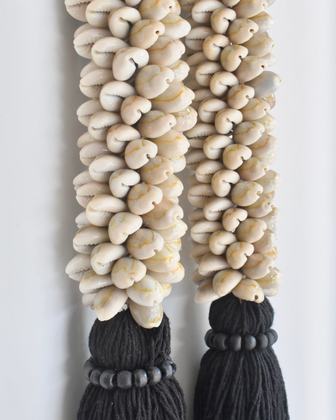 Decorative wall hanging with beads and tassels on a plain background