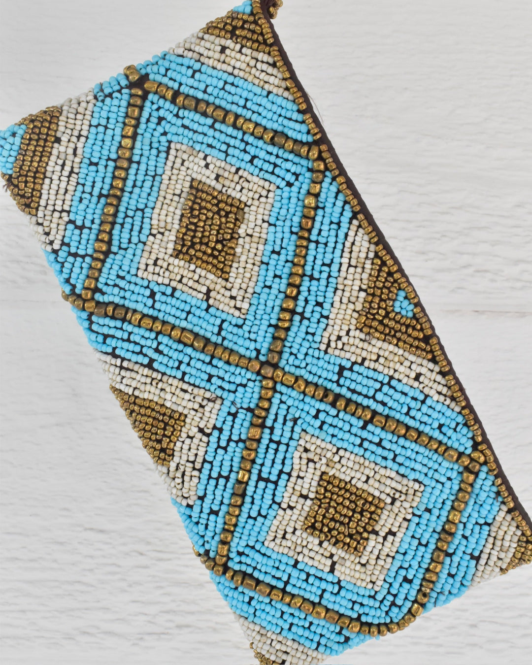  blue, brown, and beige geometric pattern beaded clutch on a light gray background