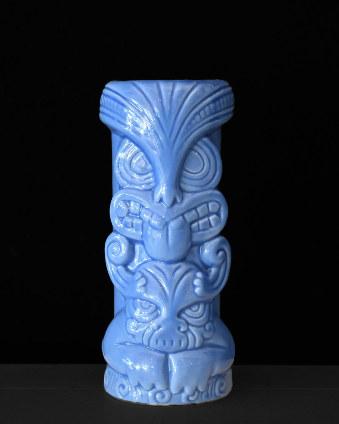 Blue tiki mug with intricate designs on a black background