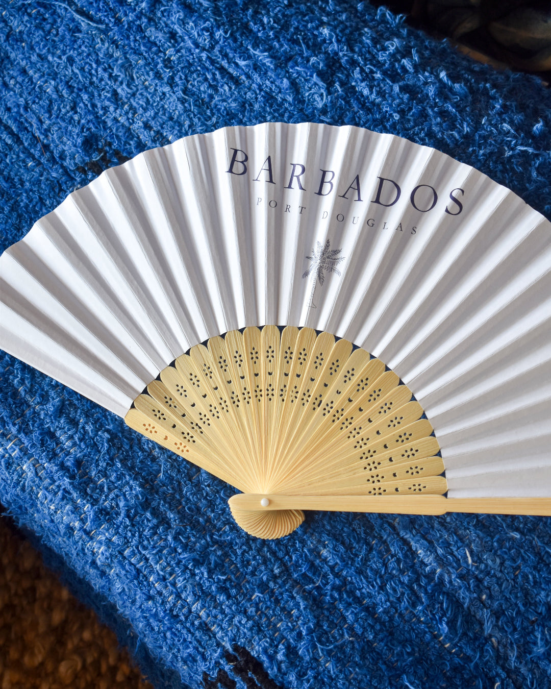 Handheld fan with 'Barbados' text on a blue textured surface