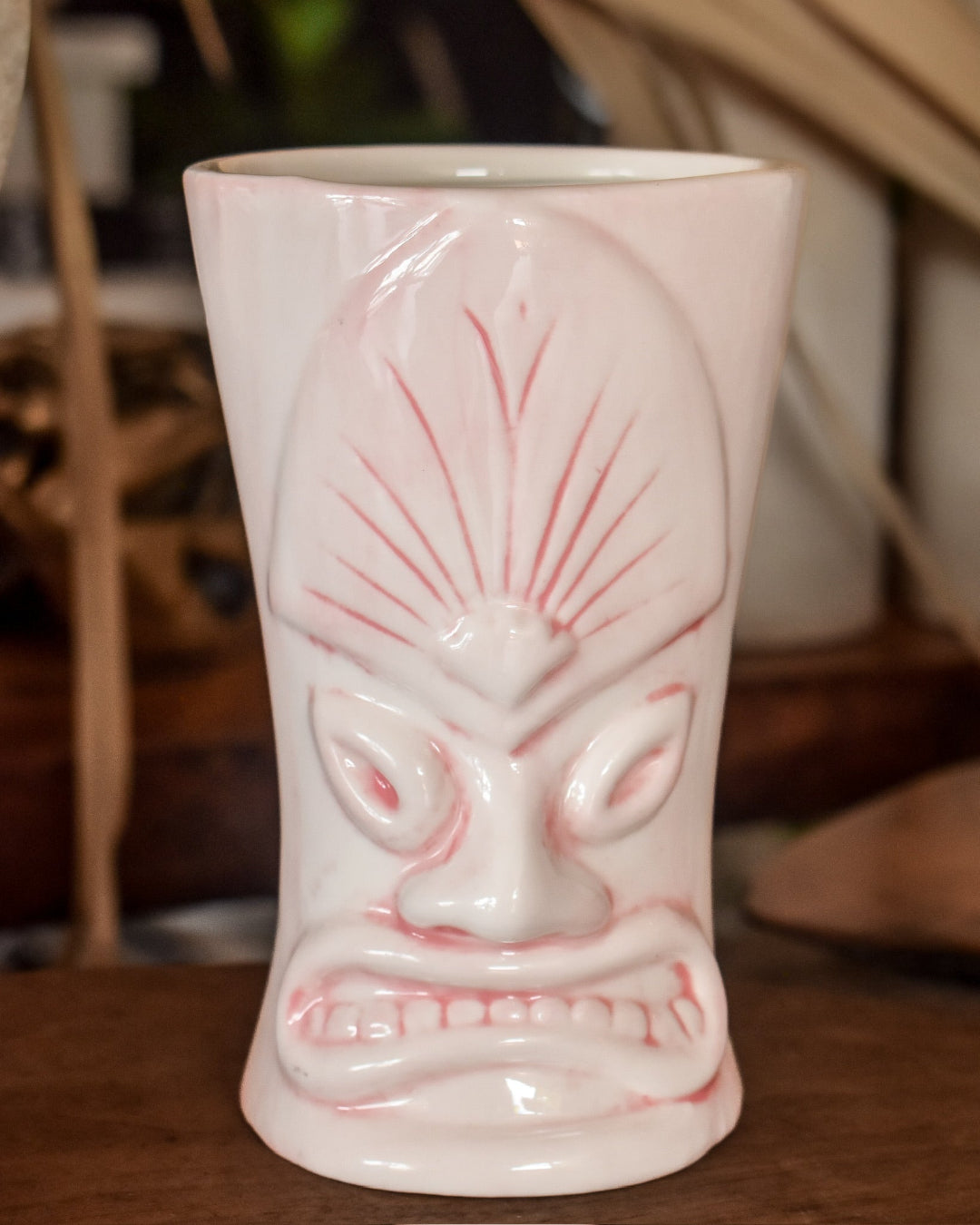 Ceramic tiki mug with a face design on a wooden surface