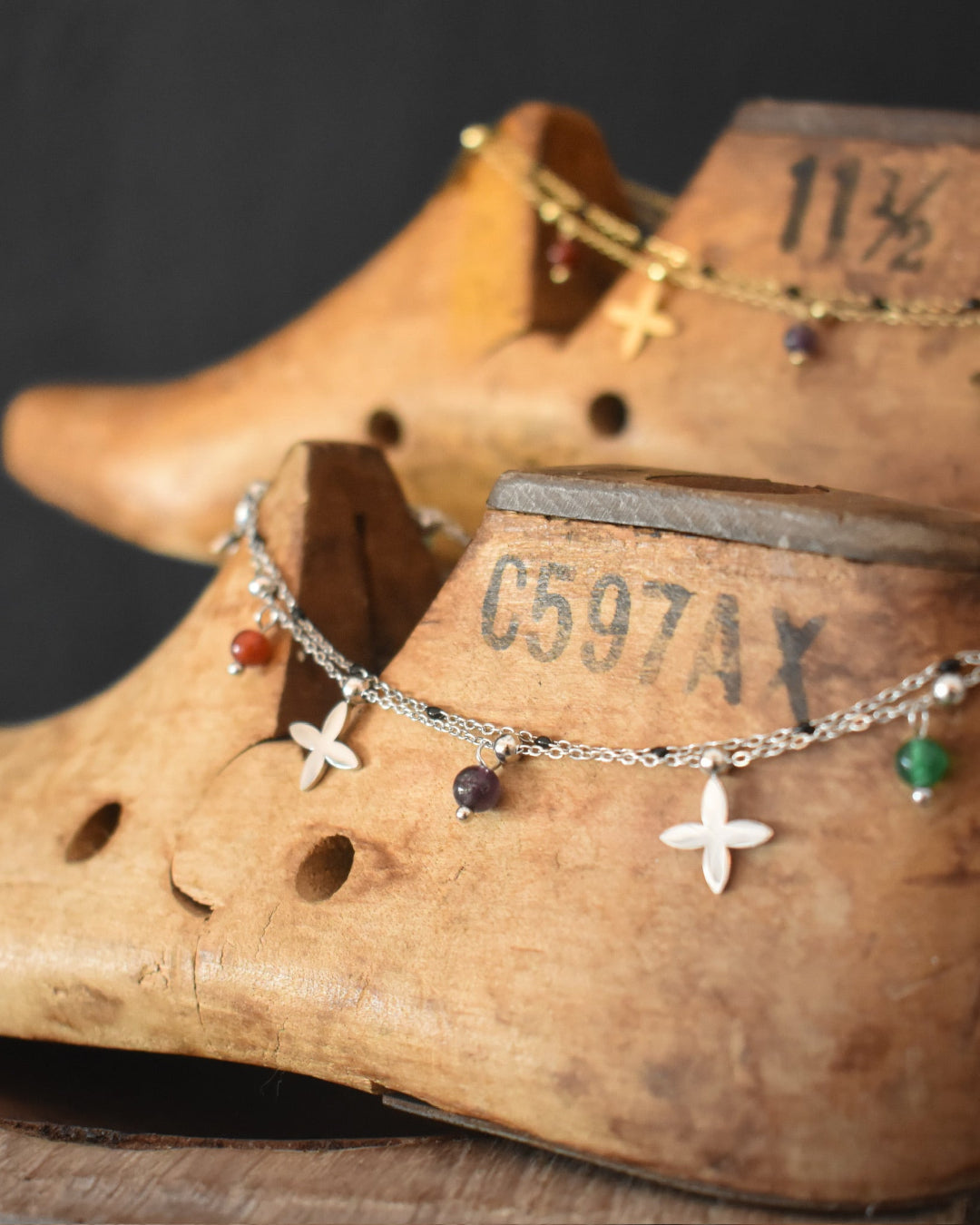Close-up of a wooden shoe last with a bracelet featuring star and gemstone charms.