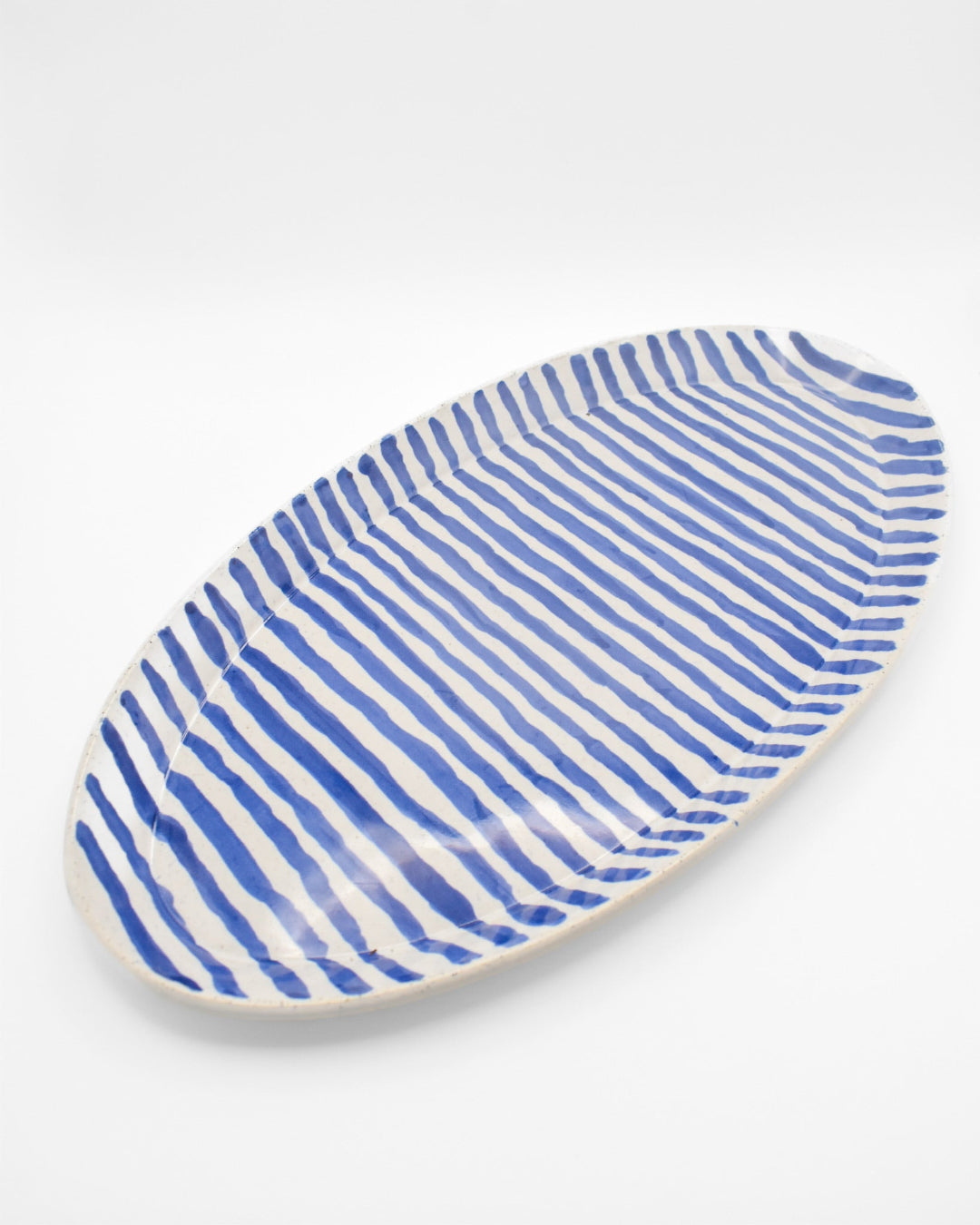 Oval ceramic plate with blue and white striped pattern on a white background