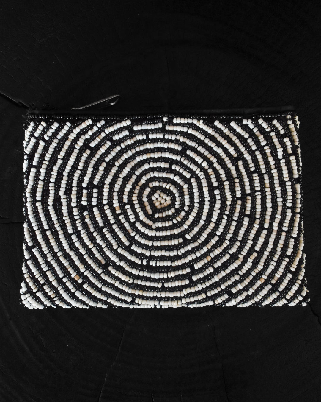 Black clutch with a spiral pattern of white beads on a black background
