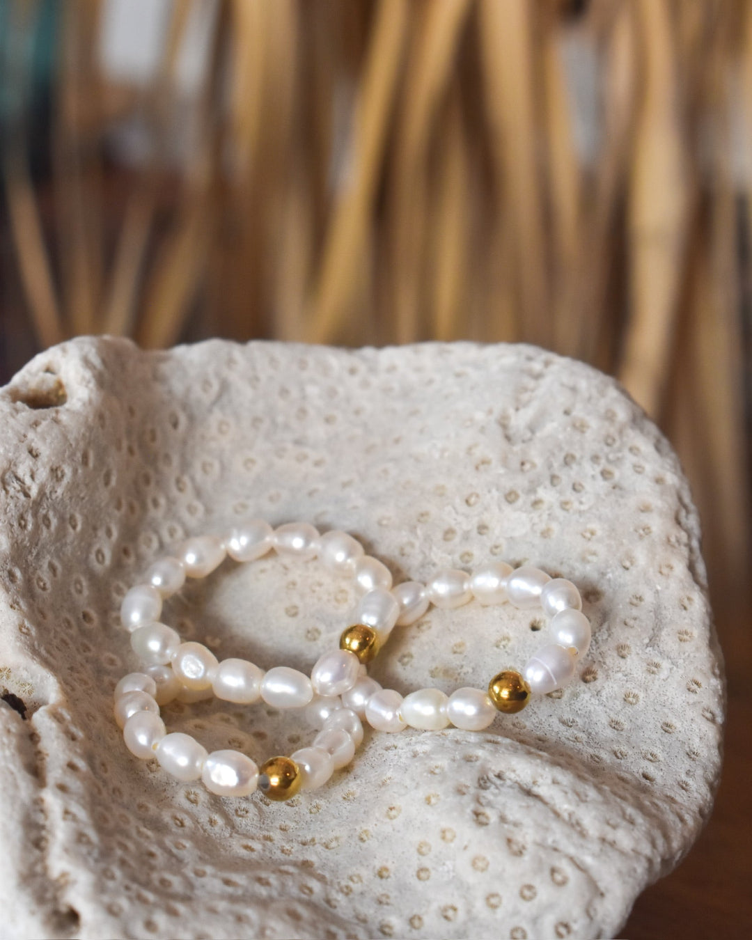 Pearl bracelet with gold accents on a piece of coral