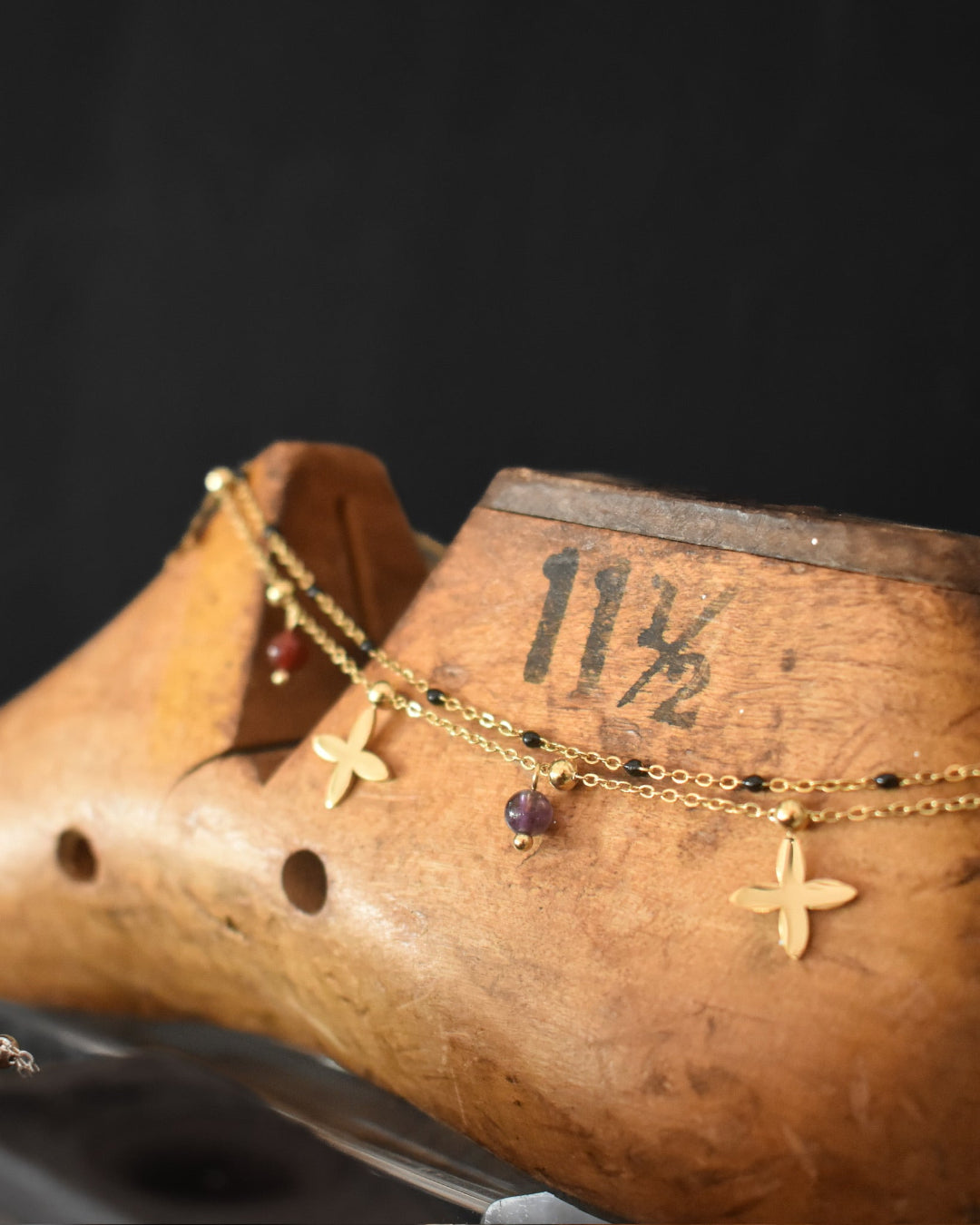 Gold necklace with gemstones on a wooden shoe