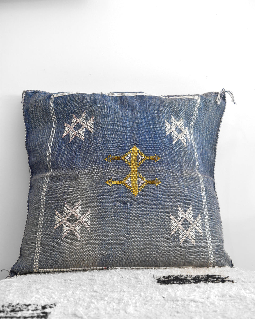Denim pillow with embroidered patterns on a white background