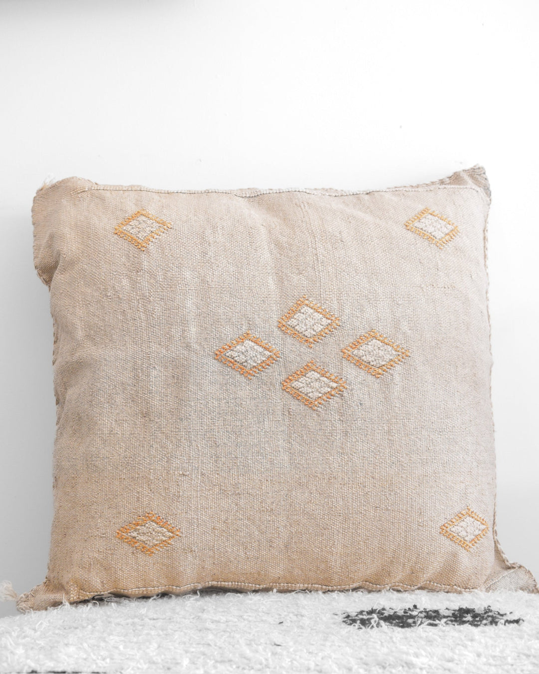 Beige pillow with diamond patterns on a white background