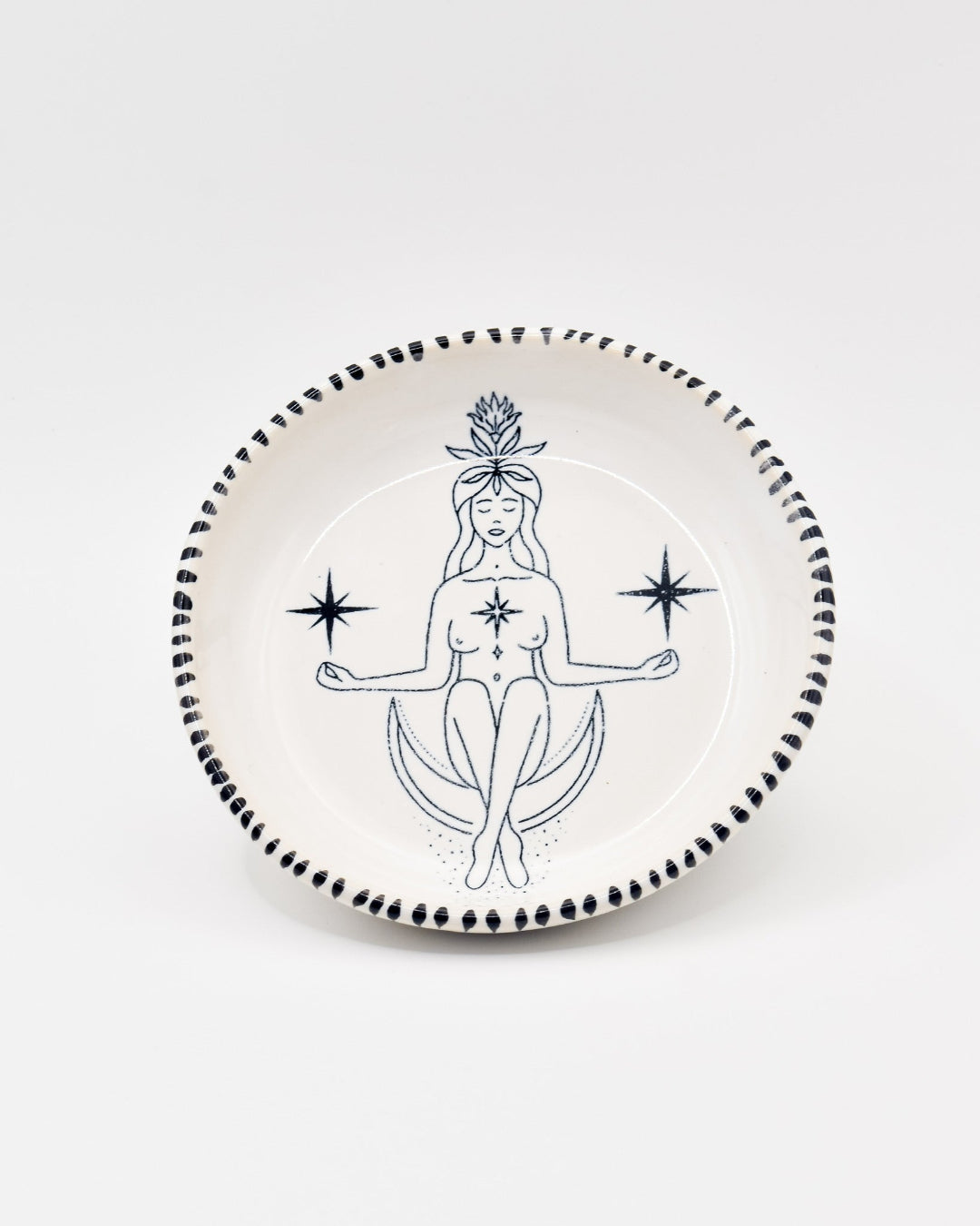 Decorative plate with a black and white illustration of a woman sitting on the moon, surrounded by stars, on a white background.