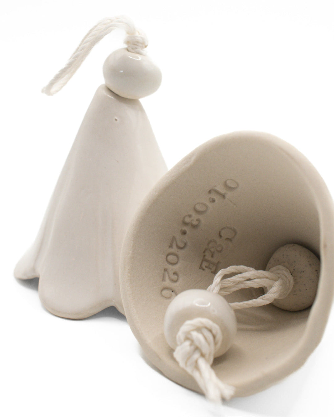 White ceramic bell with a string on a white background