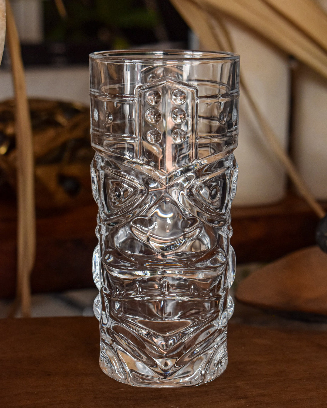 Clear textured glass tumbler on a wooden surface with a blurred background