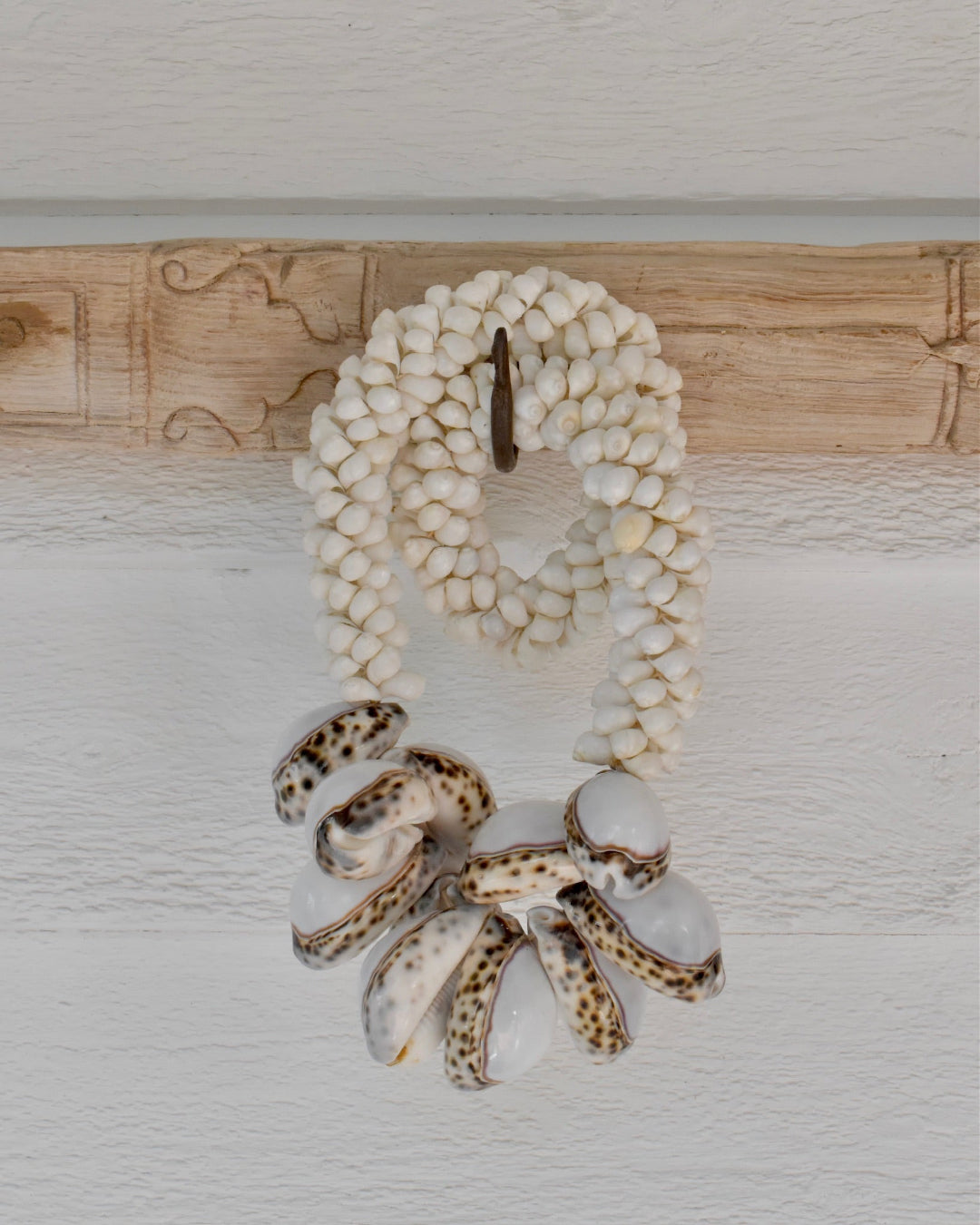 Necklace with shell beads and a large decorative clasp on a light wooden background